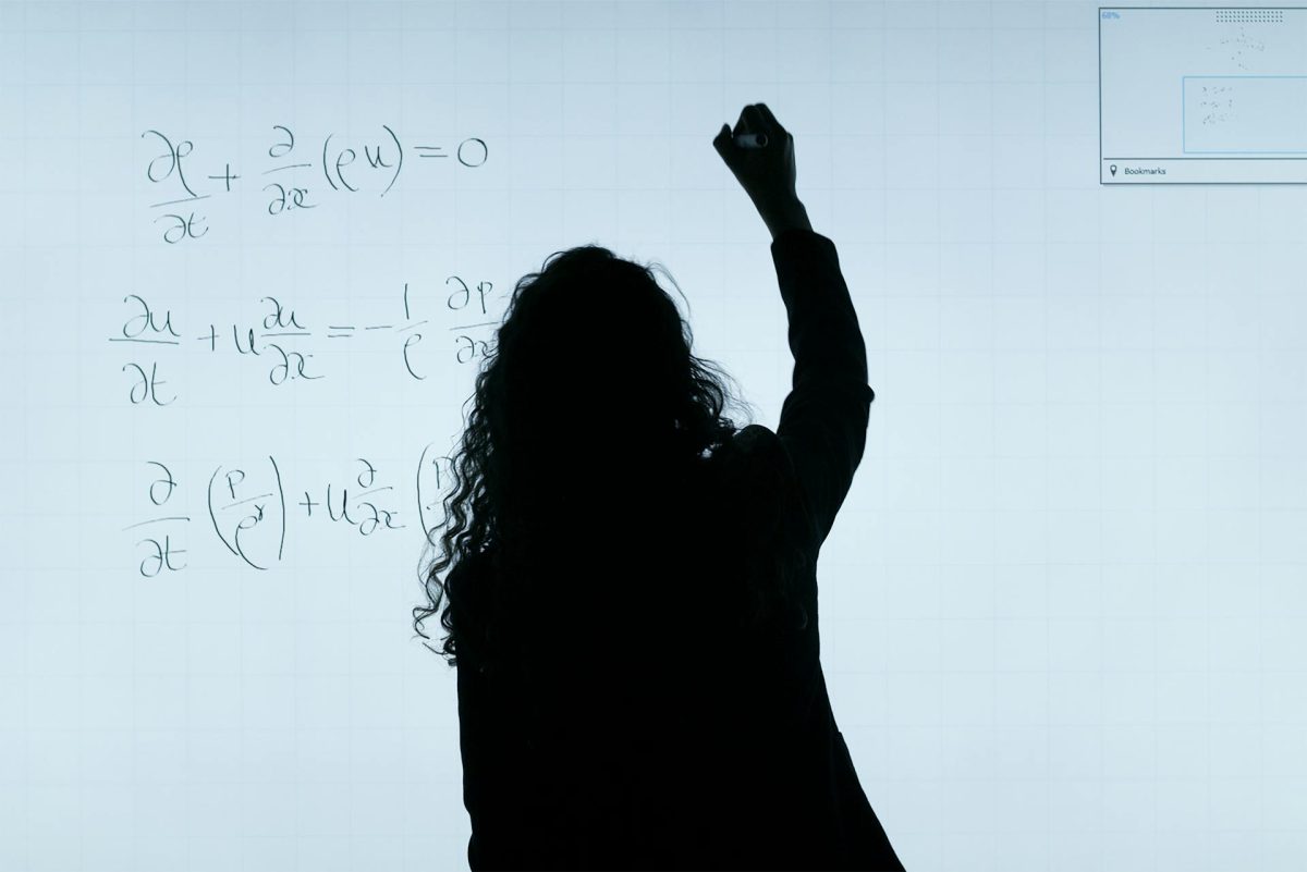Person writing complex mathematical equations on a large whiteboard or screen.