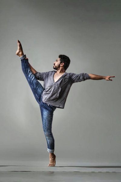 Man performing a high leg extension while balancing on one foot in a dance pose.