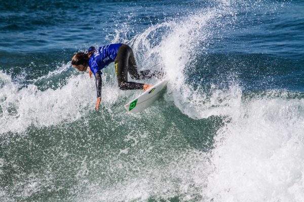 A surfer sending considerable spray on a top turn during competition in Huntington Beach, California, ca. 2017.